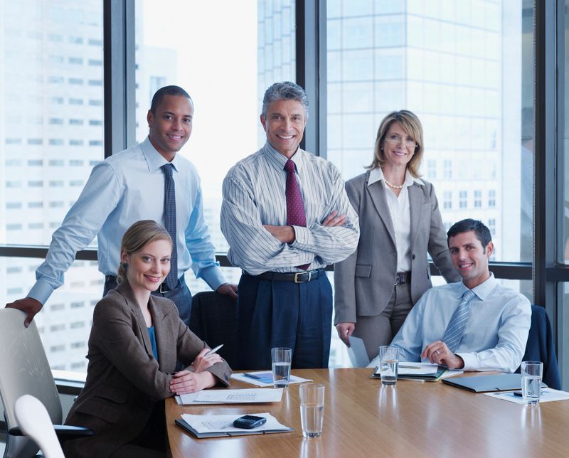 Five businesspeople in a boardroom looking at camera