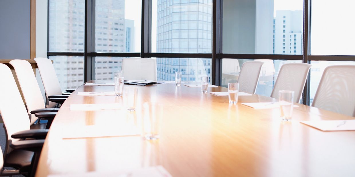 Bright modern conference room with a long wooden table and white chairs.