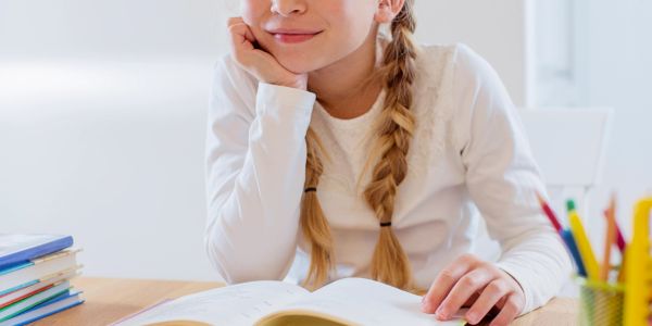 Young girl reading a book with a smile.
