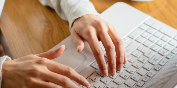Close-up of hands typing on a white laptop keyboard.