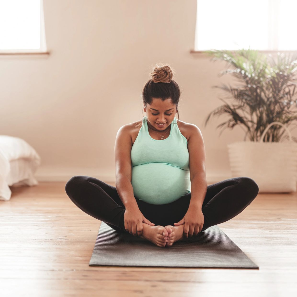 Pregnant woman doing yoga in a bright room.
