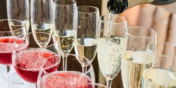 Glasses of champagne and red cocktails being served, with sparkling wine being poured into a flute.