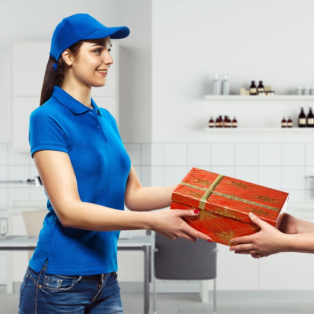 Delivery person handing over a wrapped gift box indoors.