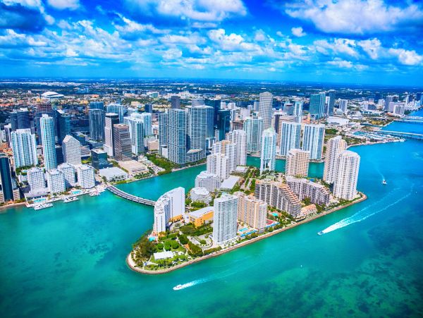 Aerial view of a coastal city with skyscrapers and turquoise waters.