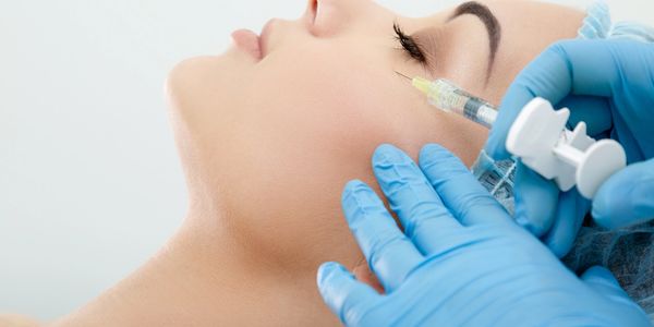 A woman receiving a cosmetic injection in her cheek.