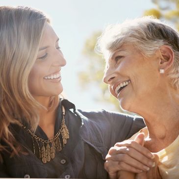 Two women smiling and holding hands outdoors.