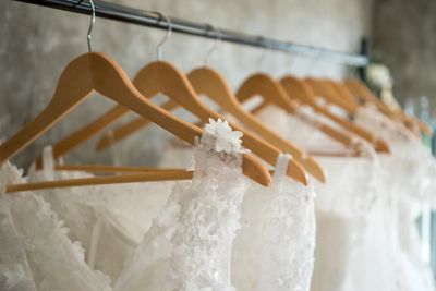 Elegant white lace wedding dresses hanging on wooden hangers.