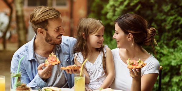 Family enjoying pizza together outdoors.