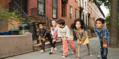 Kids in ready-to-run poses on a city sidewalk.