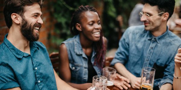 Three friends enjoying drinks and laughing together.