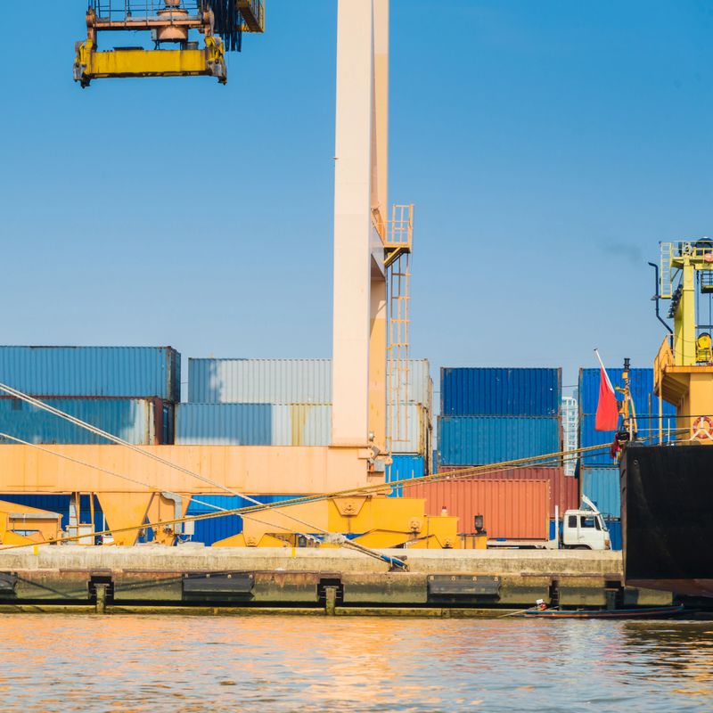 Container Cargo freight ship with working crane bridge in shipyard