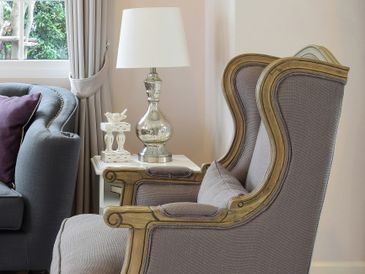 Elegant armchair and side table with a silver lamp in a cozy living room.