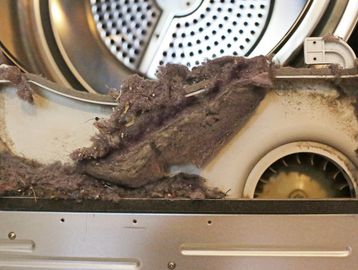 Dust and lint buildup inside a dryer vent blower wheel housing. Dryer vent cleaning and vent repair services.