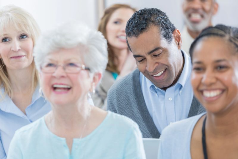 Cheerful group of diverse businesspeople attend a conference or seminar. They are laughing at the lecturer's joke.