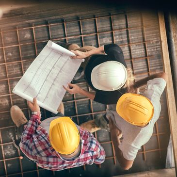 Construction workers reviewing a blueprint on a site.