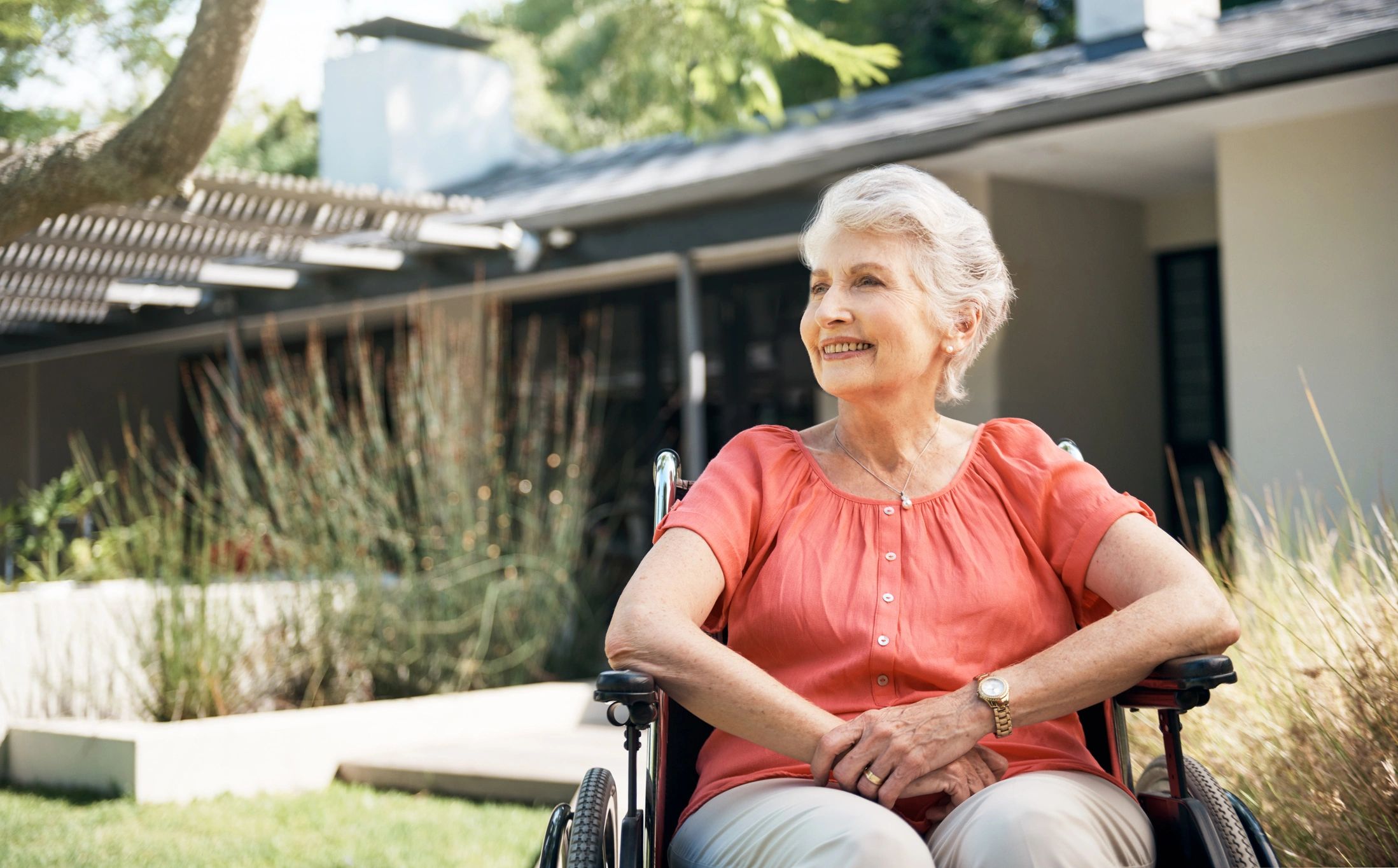 Smiling elderly woman in wheelchair outdoors.