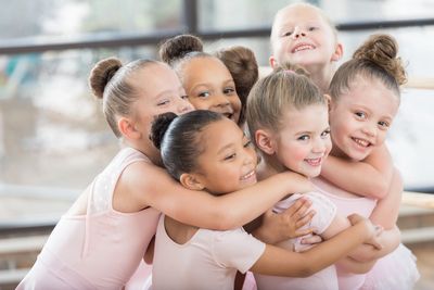 Happy young ballerinas hugging each other.