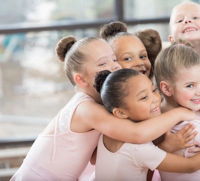 Happy young ballerinas hugging each other.