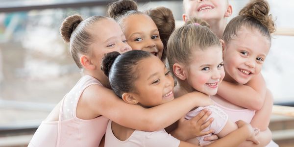 Group of happy young ballerinas hugging each other.