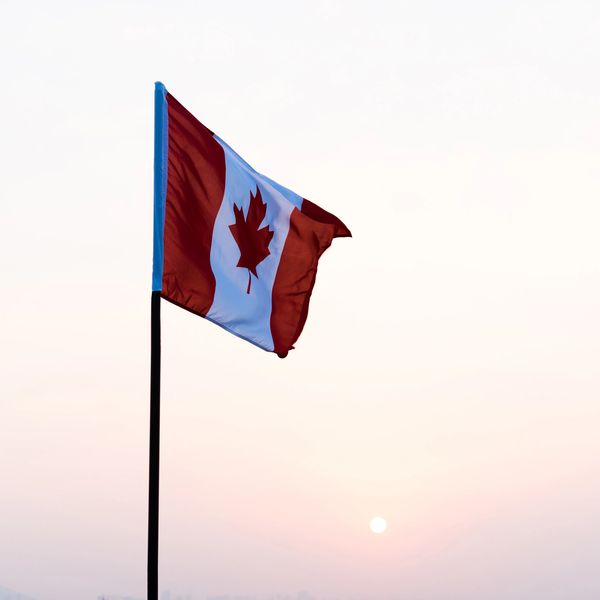 Canadian flag waving with a sunset background.