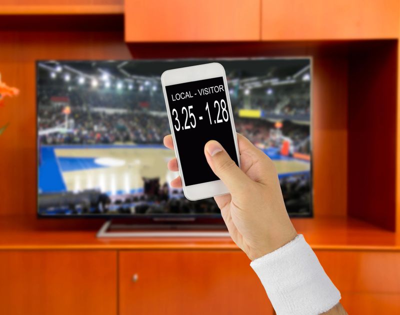 man using mobile phone and betting during a basketbal match