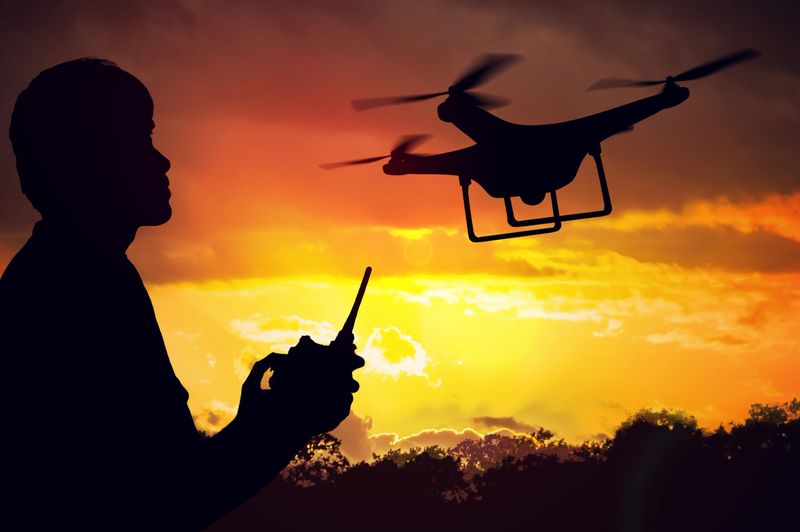 Silhouette of man controlling a drone at sunset.