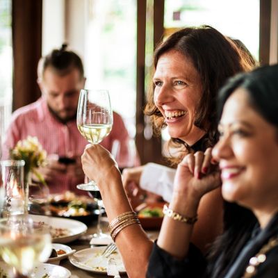 Des amis riant et buvant du vin lors d'un repas social.