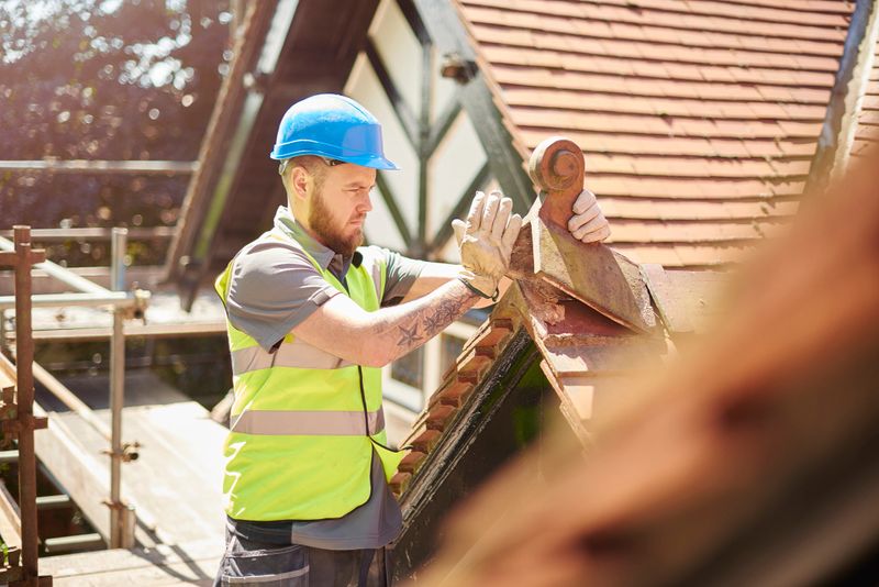 a builder or roofer is removing a finial on a roof of a period property in england .