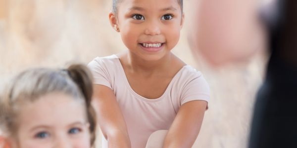 Young girl smiling while participating in a dance or exercise class.