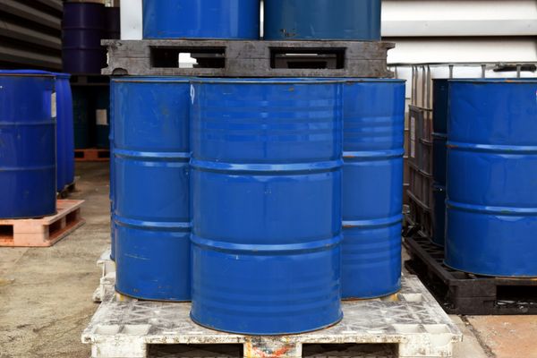 Stacked blue industrial barrels on pallets.