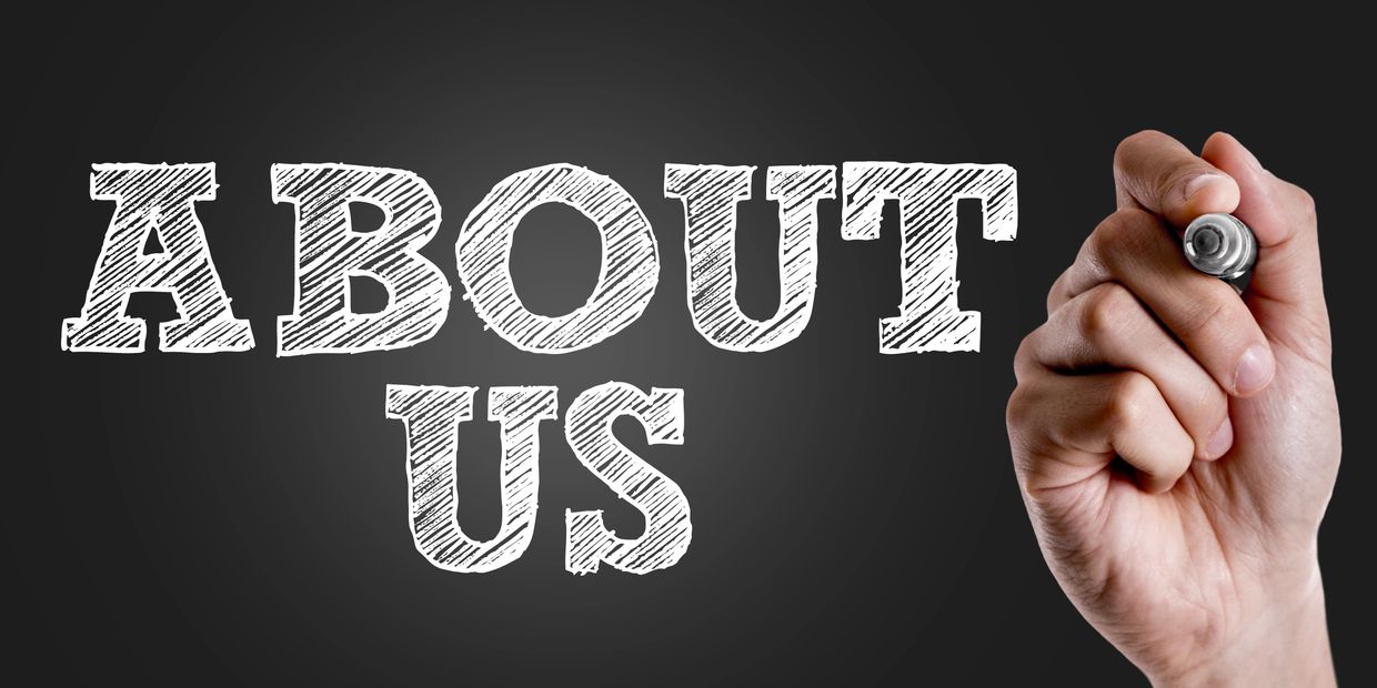 Hand writing 'ABOUT US' in chalk style on blackboard.