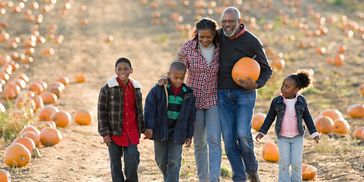 Family walking in a pumpkin patch with pumpkins around.