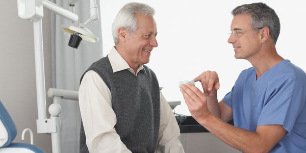 Dentist explaining dentures to an elderly man.