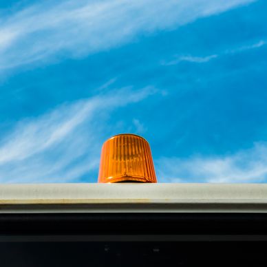 Orange warning light against blue sky.