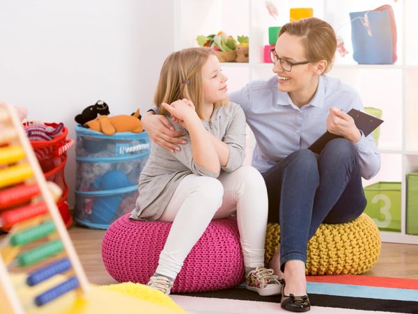 A woman and child sitting on poufs in a colorful playroom, sharing a warm moment.