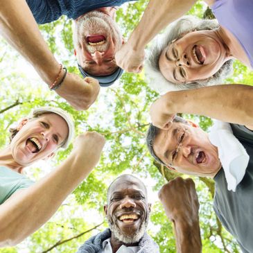 A joyful group of elderly friends cheering together outdoors.