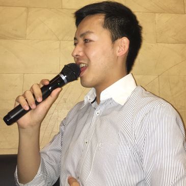 Man singing into a microphone, wearing a striped shirt.