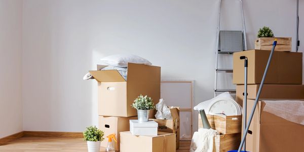 Packed moving boxes and cleaning tools in a bright, empty room.