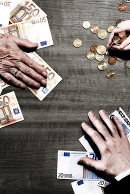 Two people counting euros and coins on a table.