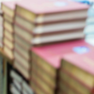 Blurred stacks of books with yellowed pages and red covers.