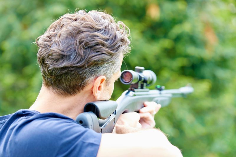 Rear view shot of a man with airgun practicing at the shooting range.