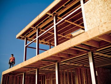 Framed house under construction against a blue sky.
