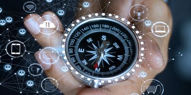 Compass held in hand with digital icons surrounding it.