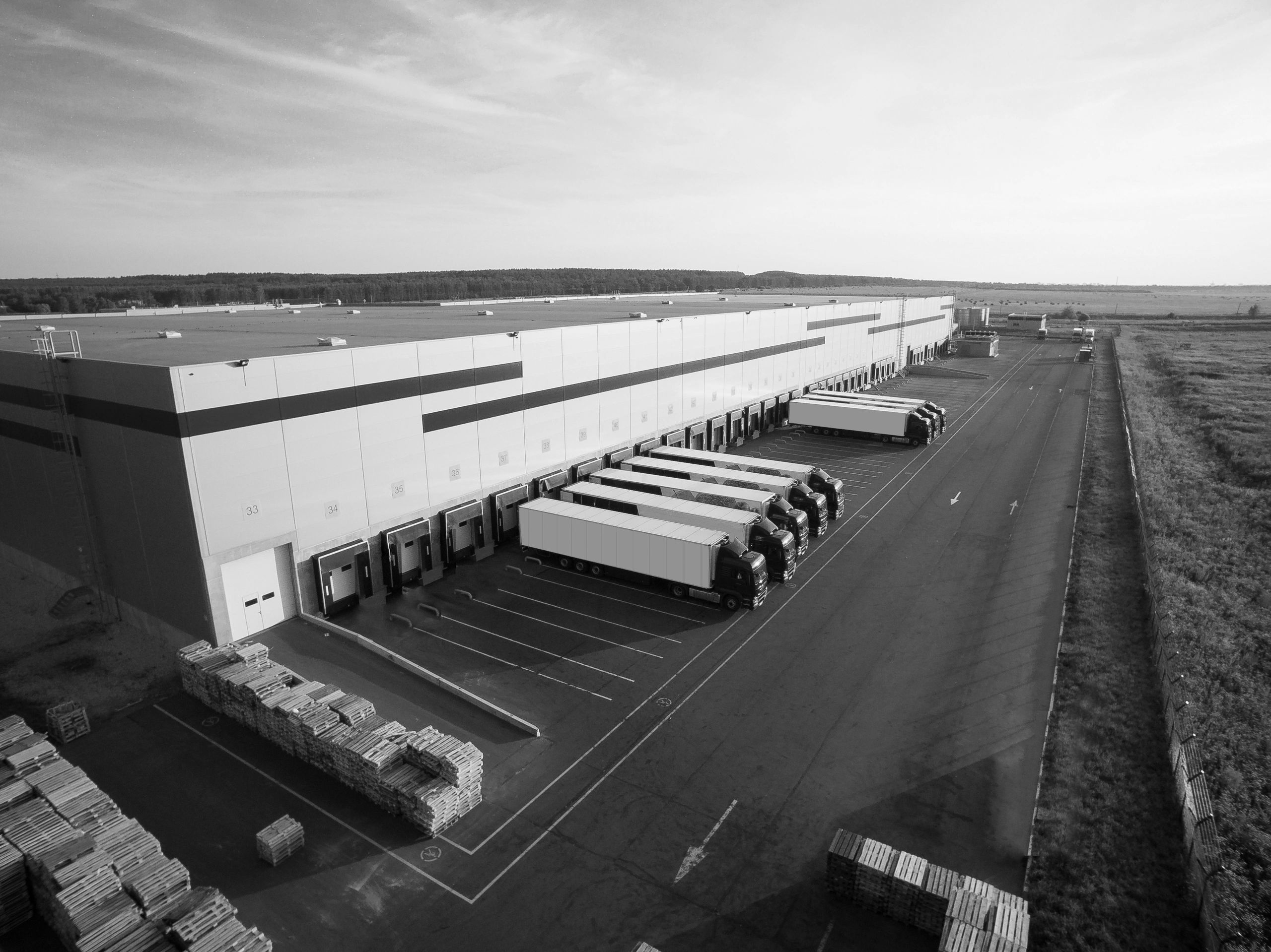 A large warehouse with multiple trucks parked at loading docks under a clear sky.