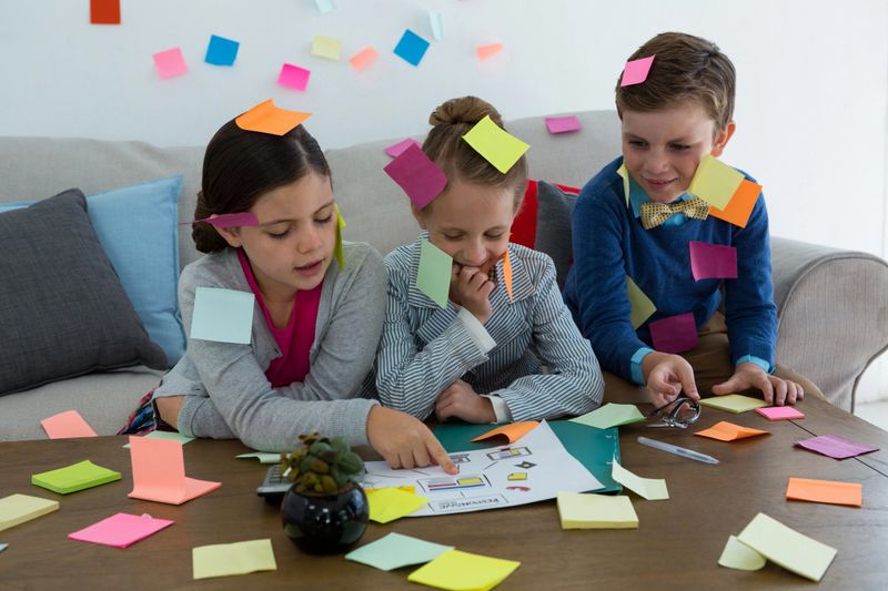 Kids as business executives playing with sticky notes in office