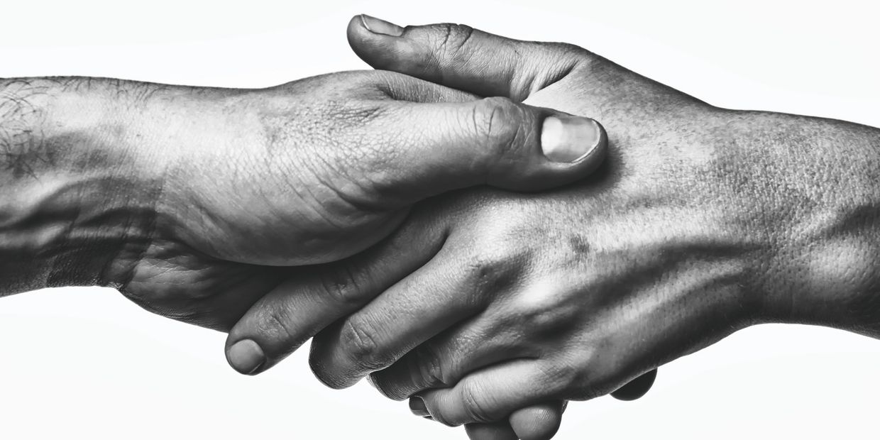 Two hands clasped tightly in a black and white close-up.