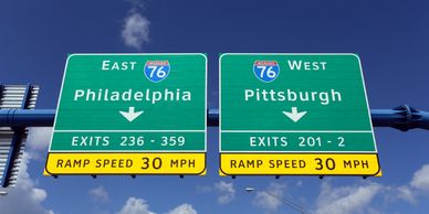 Highway signs for I-76 East to Philadelphia and I-76 West to Pittsburgh.