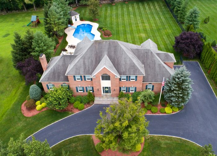 Aerial real estate photography of a brick home with pool and landscaped yard in Jackson, TN