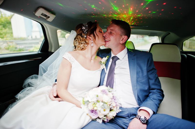 Fantastic wedding couple sitting and kissing in the limousine.