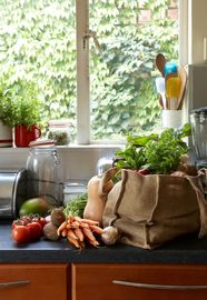 Person holding a crate filled with fresh vegetables including lettuce, tomatoes, and peppers.